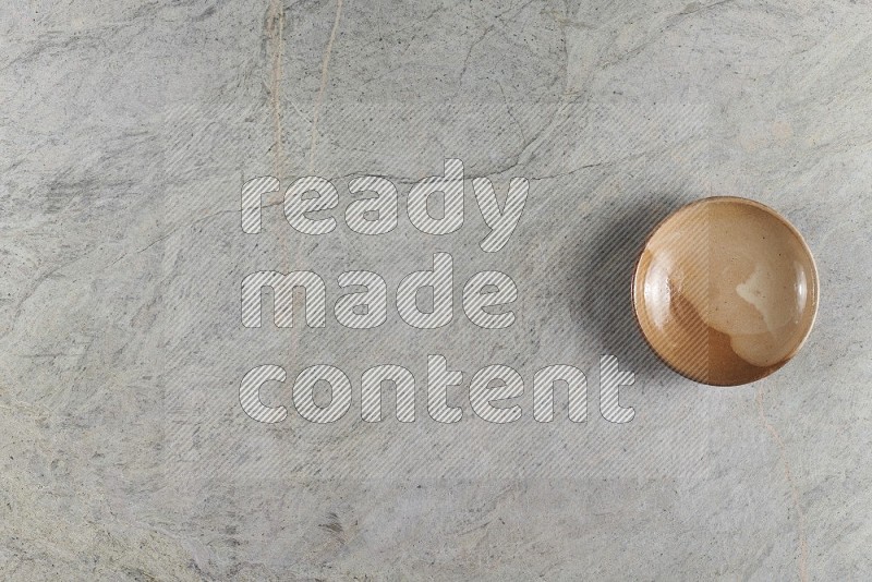 Top View Shot Of A Beige Pottery Plate On Grey Marble Flooring