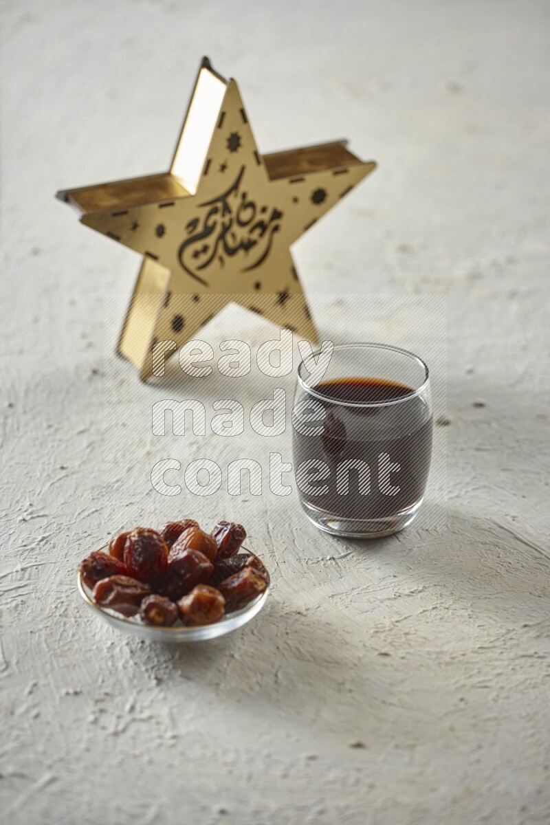 A wooden golden star lantern with different drinks, dates, nuts, prayer beads and quran on textured white background