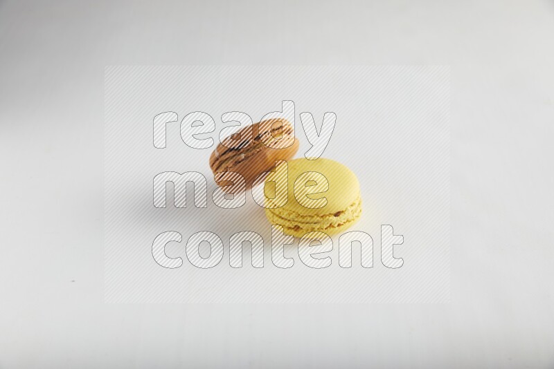 45º Shot of of two assorted Brown Irish Cream, and Yellow Lemon macarons on white background