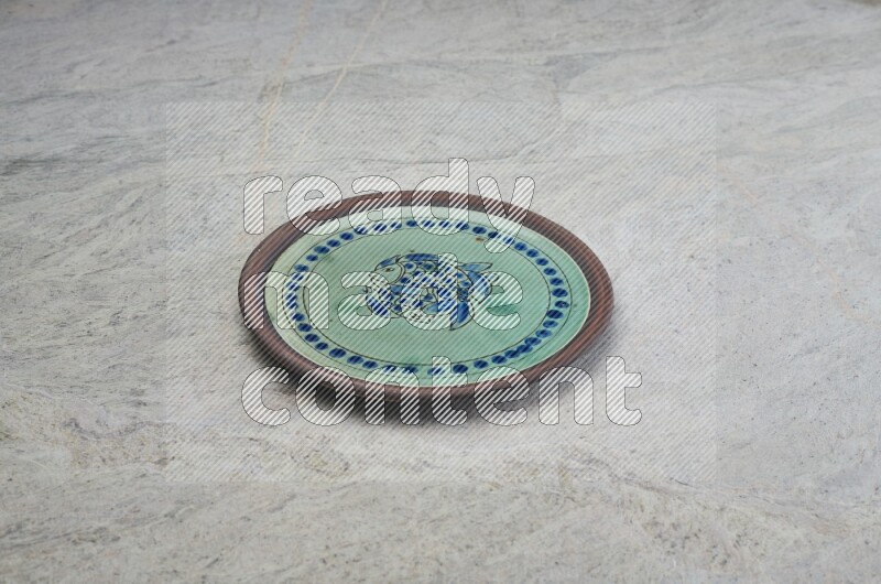 A decorative pottery plate on grey marble background