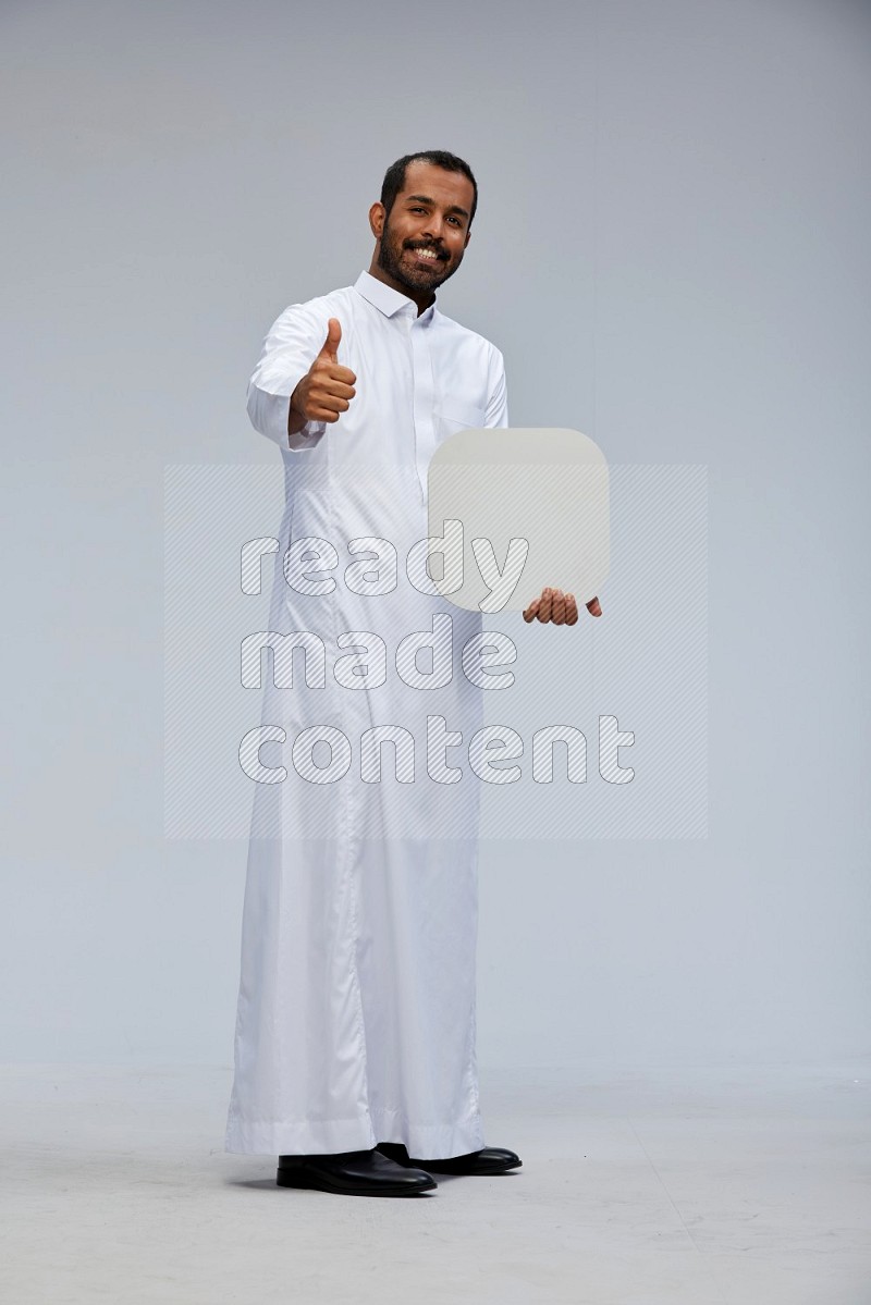 Saudi man wearing Thob standing holding social media sign on Gray background