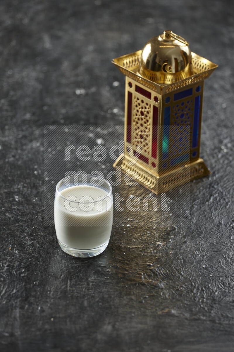 A golden lantern with different drinks, dates, nuts, prayer beads and quran on textured black background