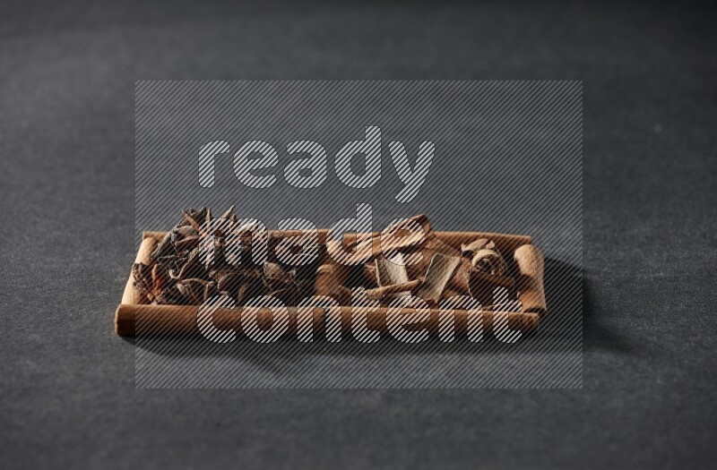 مربعان من أعواد القرفة ممتلئان باليانسون النجمي وقطع من القرفة علي خلفية سوداء