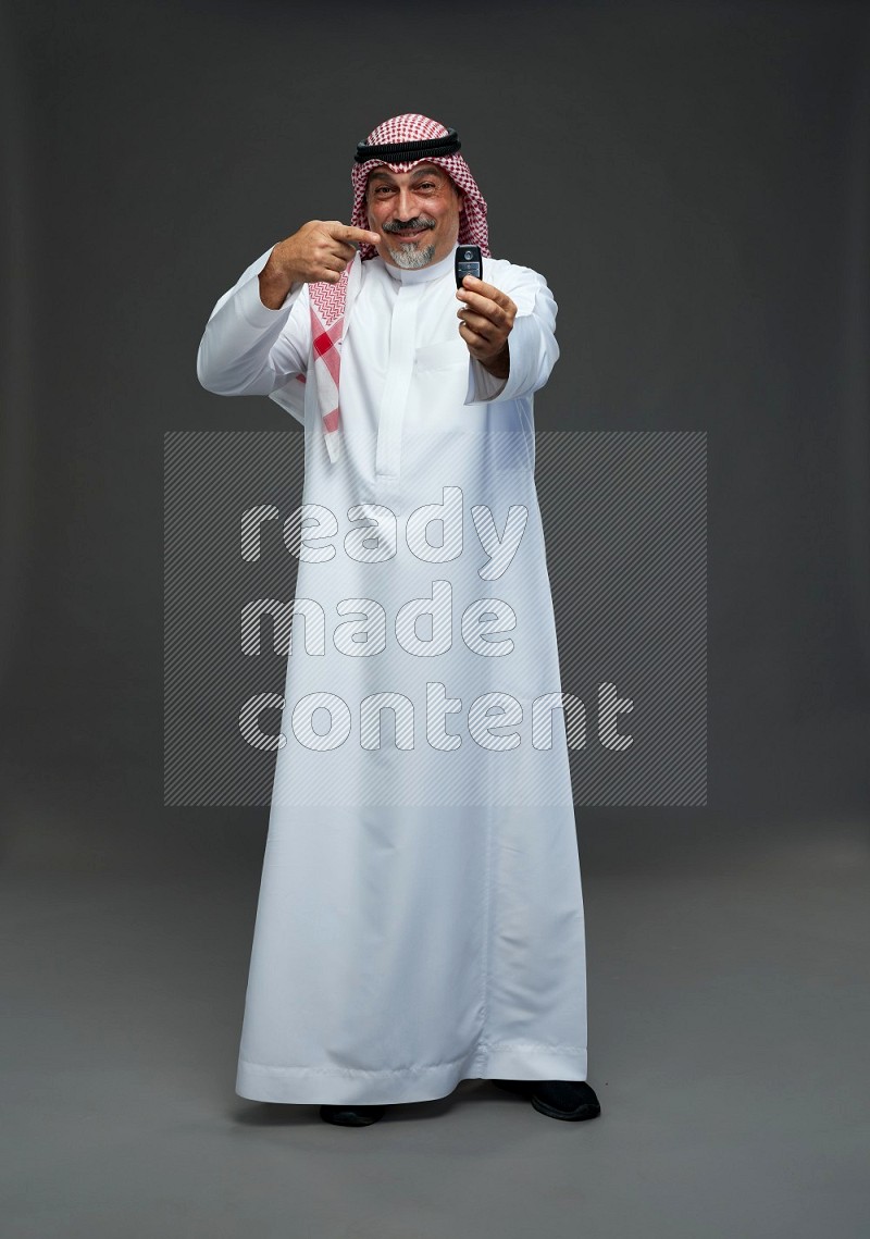 Saudi man with shomag Standing holding car key on gray background