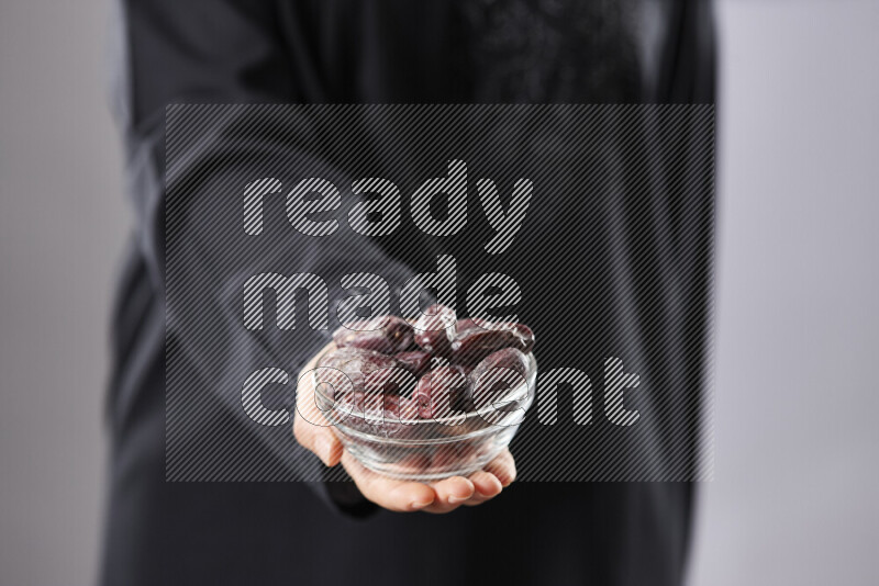 Woman in abaya holding dates in different positions