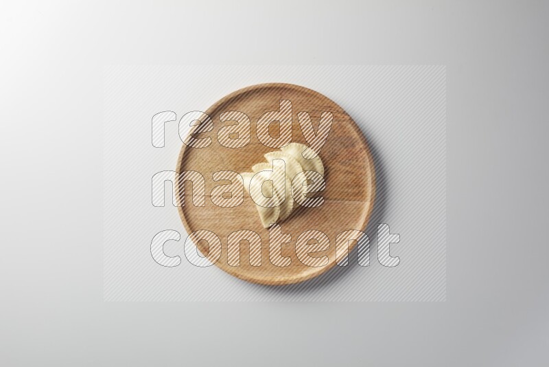 Four Sambosas on a wooden round plate on a white background