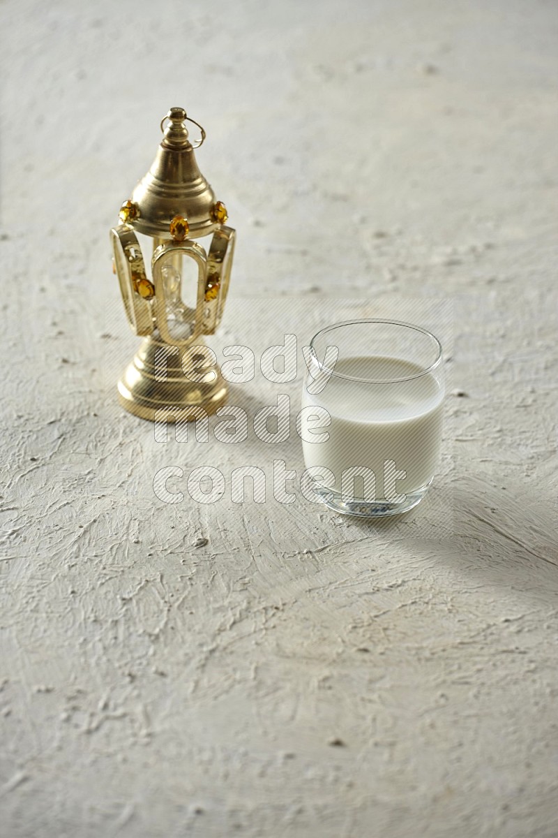 A golden lantern with different drinks, dates, nuts, prayer beads and quran on textured white background