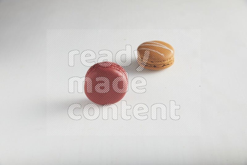 45º Shot of of two assorted Brown Irish Cream, and Red Velvet macarons on white background