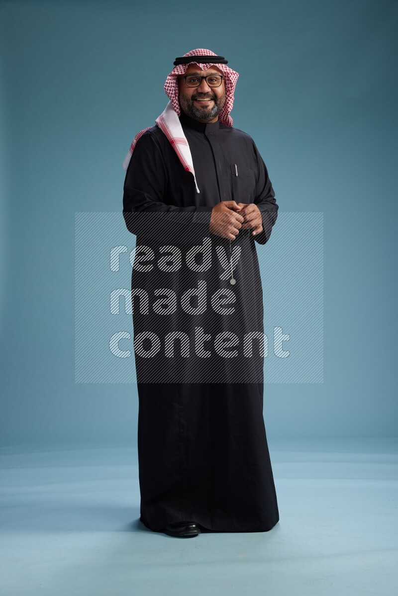 Saudi Man with shimag Standing Interacting with the camera on blue background