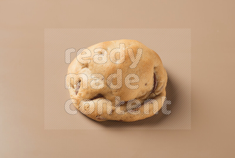 a whole chocolate chip cookie on a brown background