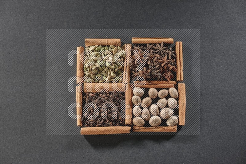 4 squares of cinnamon sticks full of cardamom, star anise, nutmegs and cloves on black flooring