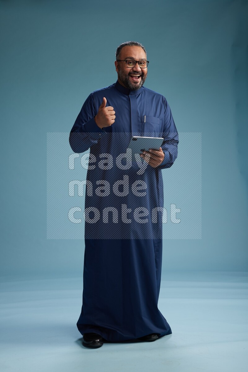 Saudi Man without shimag Standing working on tablet on blue background