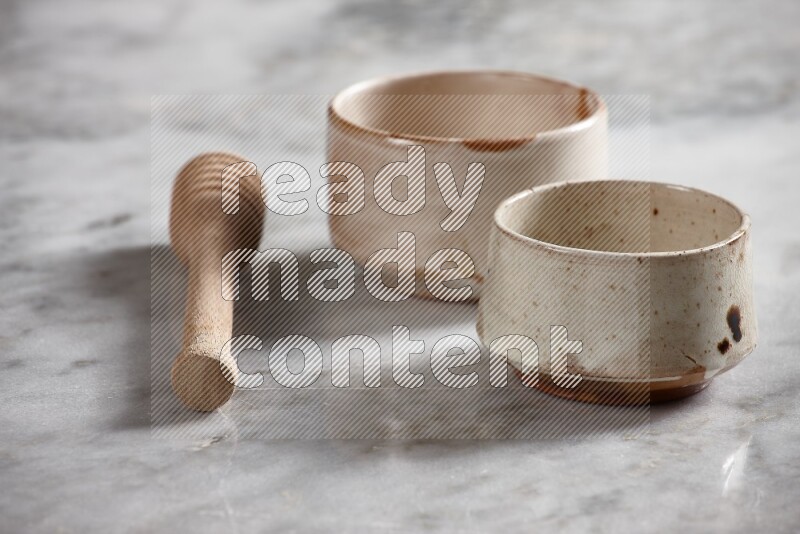 Multicolored pottery bowls with wooden honey dipper on the side on grey marble background