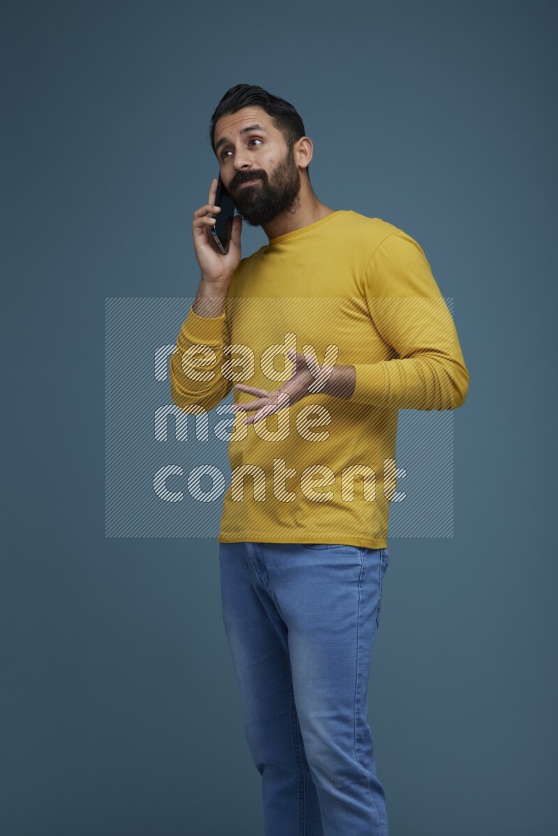 A man having a calling in a blue background wearing a yellow shirt