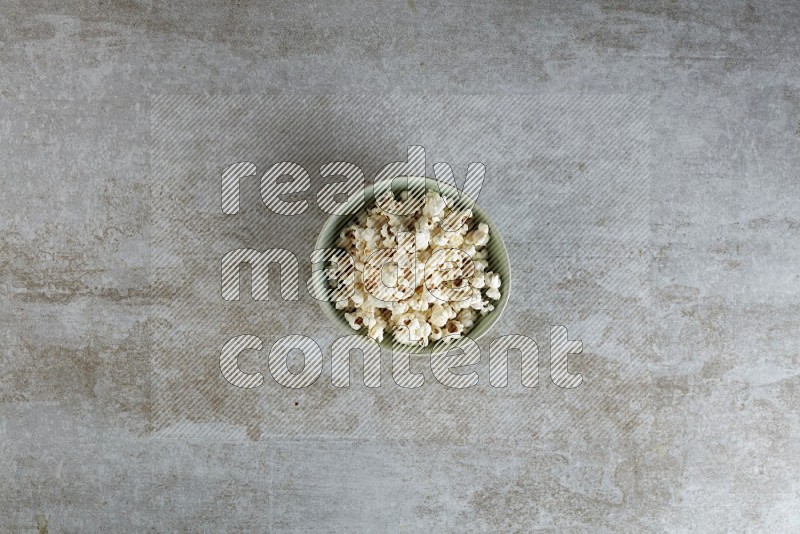 popcorn in green bowl on a grey textured countertop
