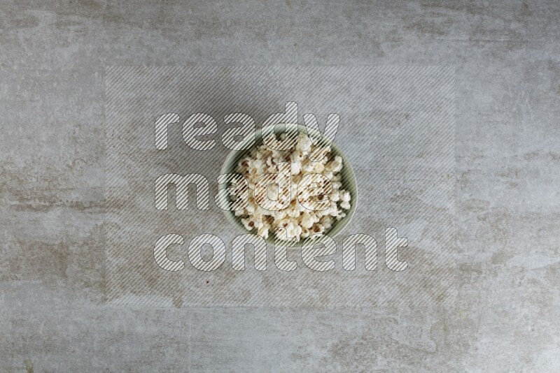 popcorn in green bowl on a grey textured countertop