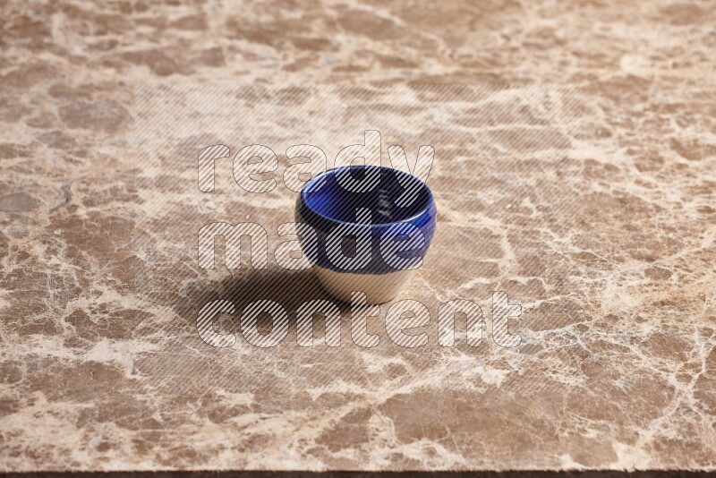 A multicolored pottery cup on beige marble background