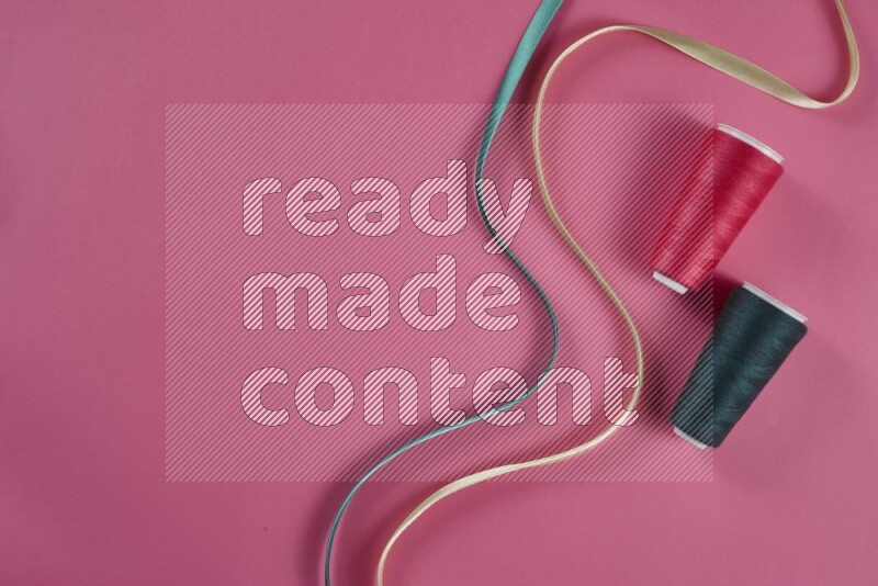 مجموعة من أدوات الخياطة والتفصيل خضراء وزهرية اللون على خلفية زهرية