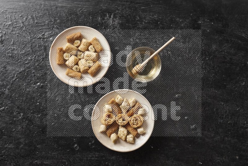 Oriental sweets in pottery plates with honey in a dark setup