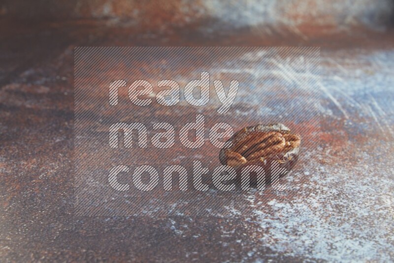 one pecan stuffed madjoul date on a rustic reddish background
