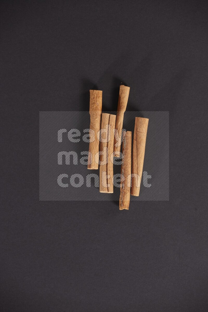 Cinnamon sticks stacked on black flooring