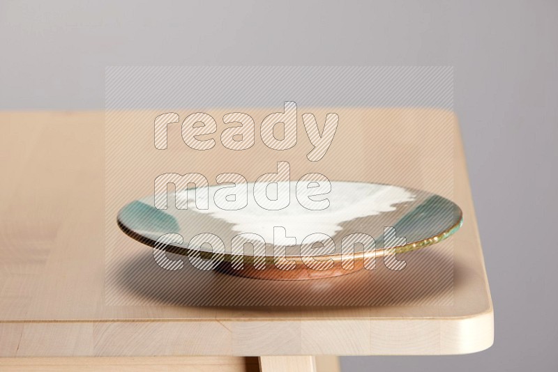 multi-colored pottery Plate on a wooden table edge