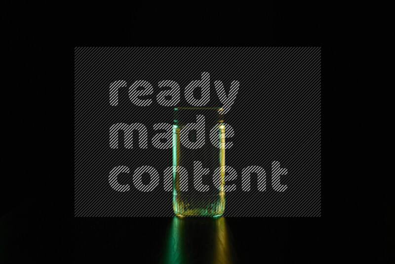 Glassware with rim light in green and yellow against black background