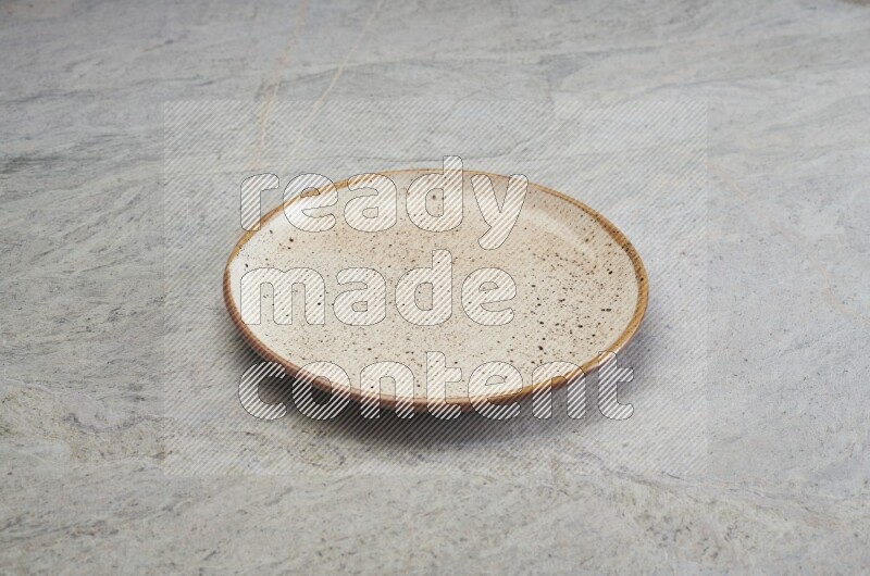 A beige pottery plate on grey marble background