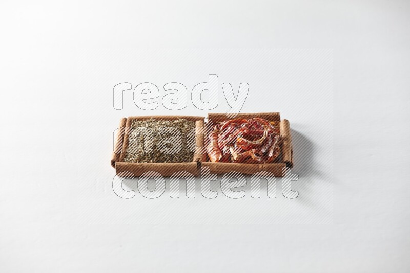 مربعان من أعواد القرفة ممتلئان بالفلفل الحار المجفف وحبوب الكمون علي خلفية بيضاء