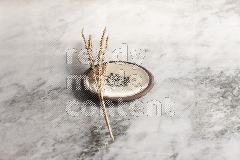 Wheat stalks on decorative pottery plate on grey marble background