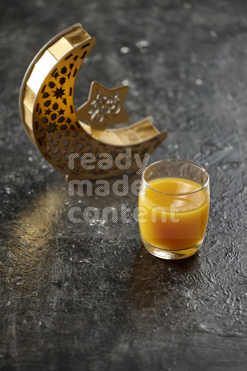 A wooden golden crescent lantern with different drinks, dates, nuts, prayer beads and quran on textured black background