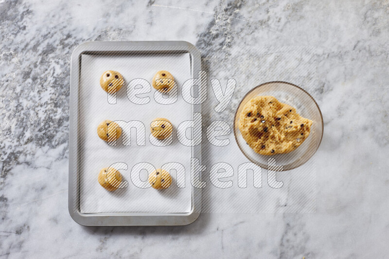Cookies step by step with its ingredient, flour, butter, brown sugar, egg, vanilla extract, white sugar, chocolate chips and baking soda on grey marble background