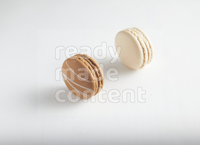 45º Shot of of two assorted Brown Irish Cream, and White Caramel fleur de sel macarons on white background