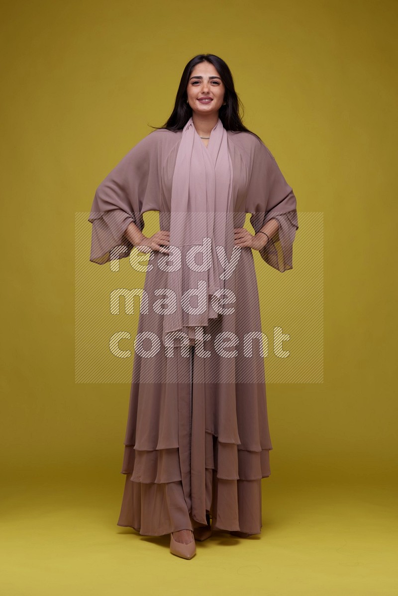 A woman Posing on a Yellow Background wearing Brown Abaya