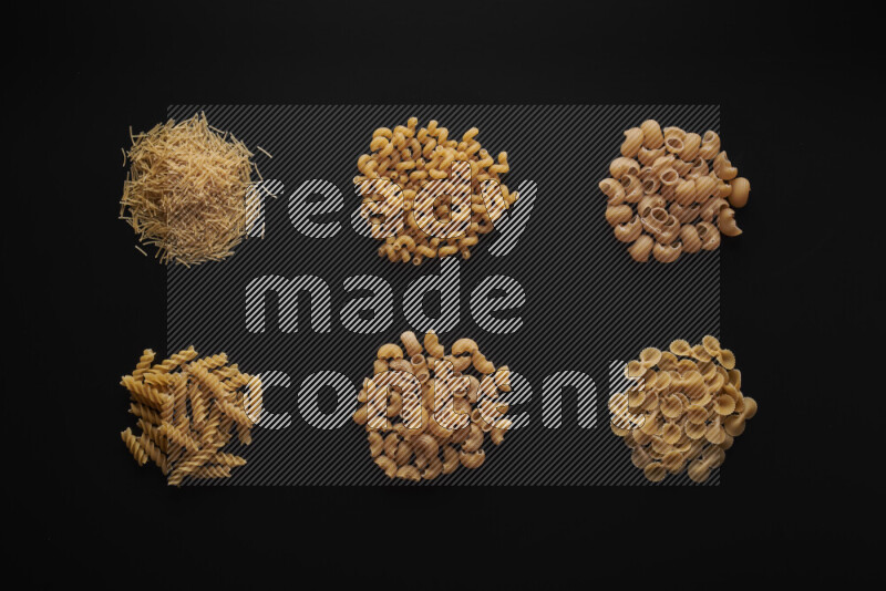 Different pasta types in bunches on black background