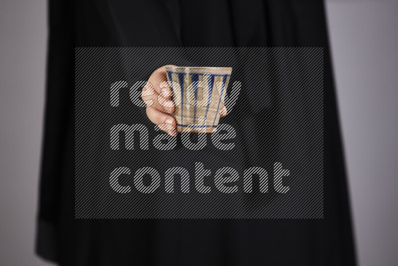A woman in black abaya holding different pottery essentials in different positions