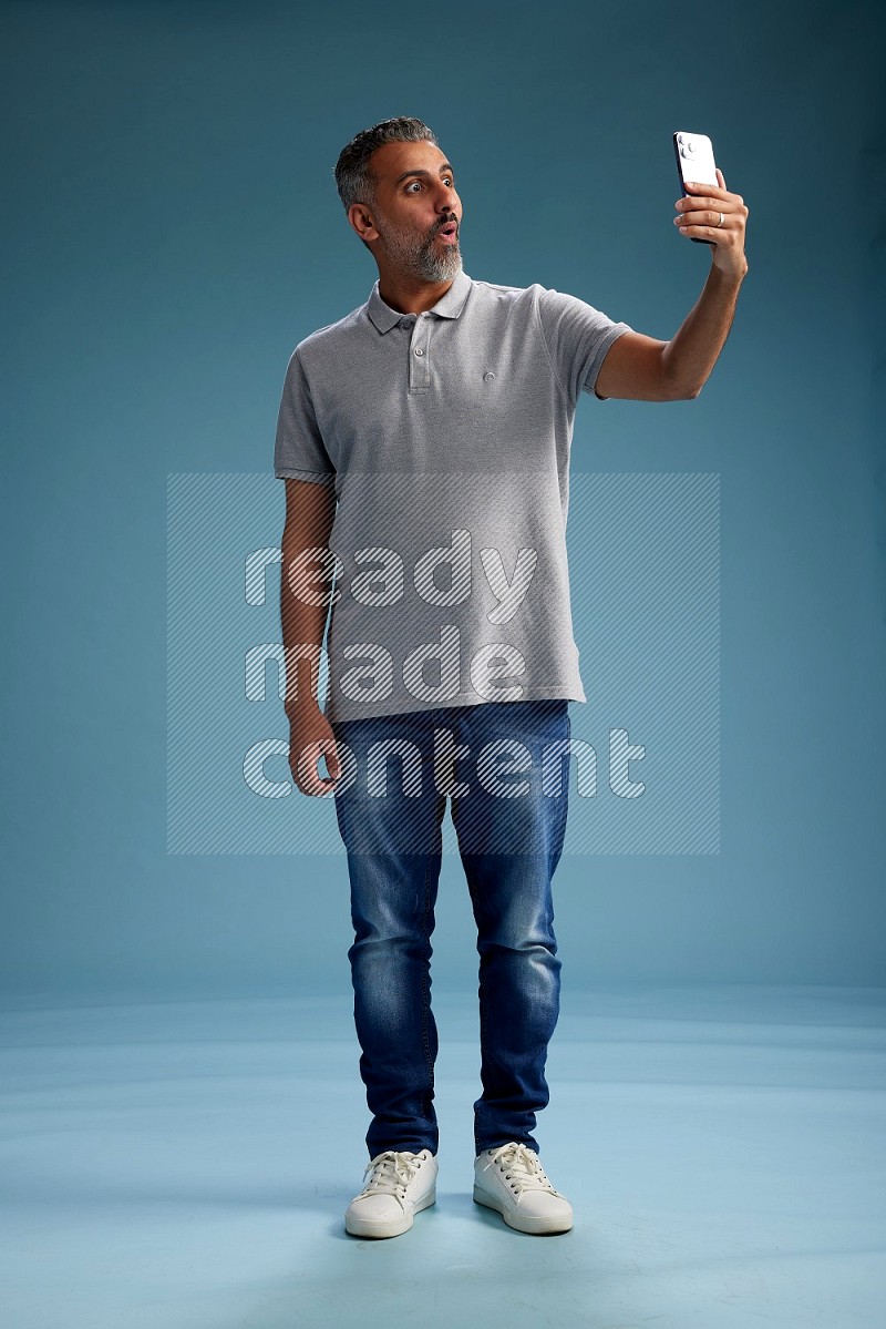 Man Standing taking selfie on blue background