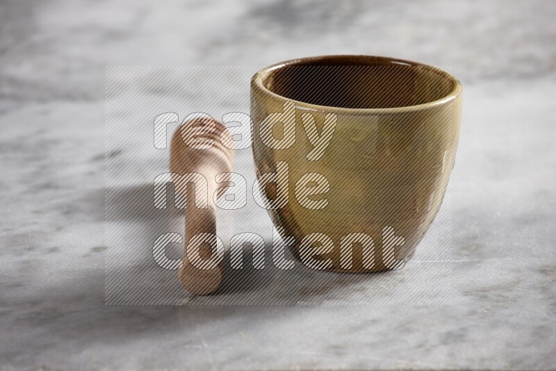 Multicolored pottery cup with wooden honey dipper on the side on grey marble background