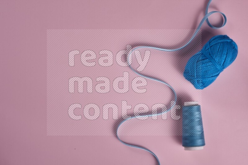 A blue collection of sewing and tailoring tools arranged on a pink background