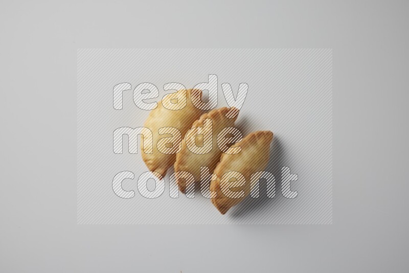 Three fried sambosa from a top angle on a white background