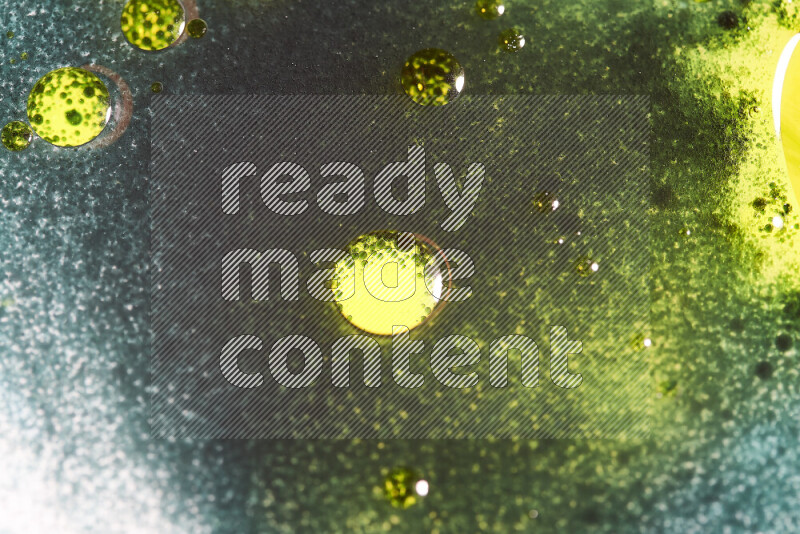 Close-ups of abstract green and yellow watercolor drops on oil Surface on white background