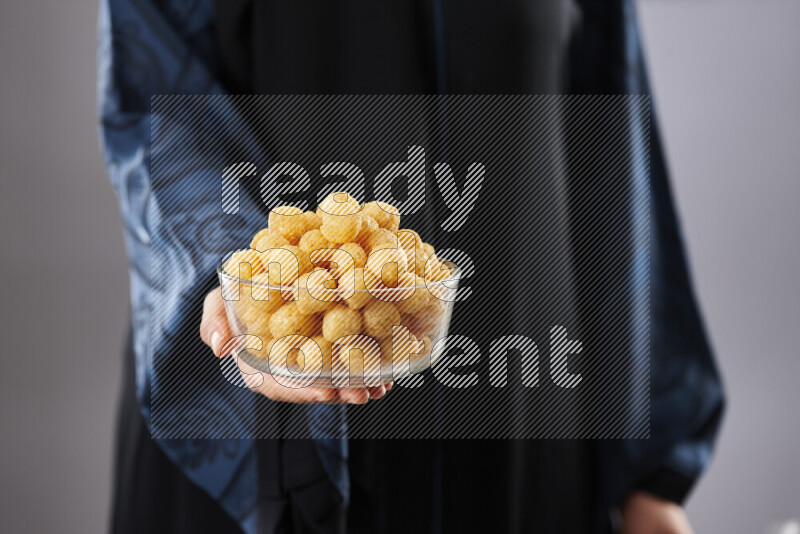 Woman in abaya holding different kinds of snacks in different positions