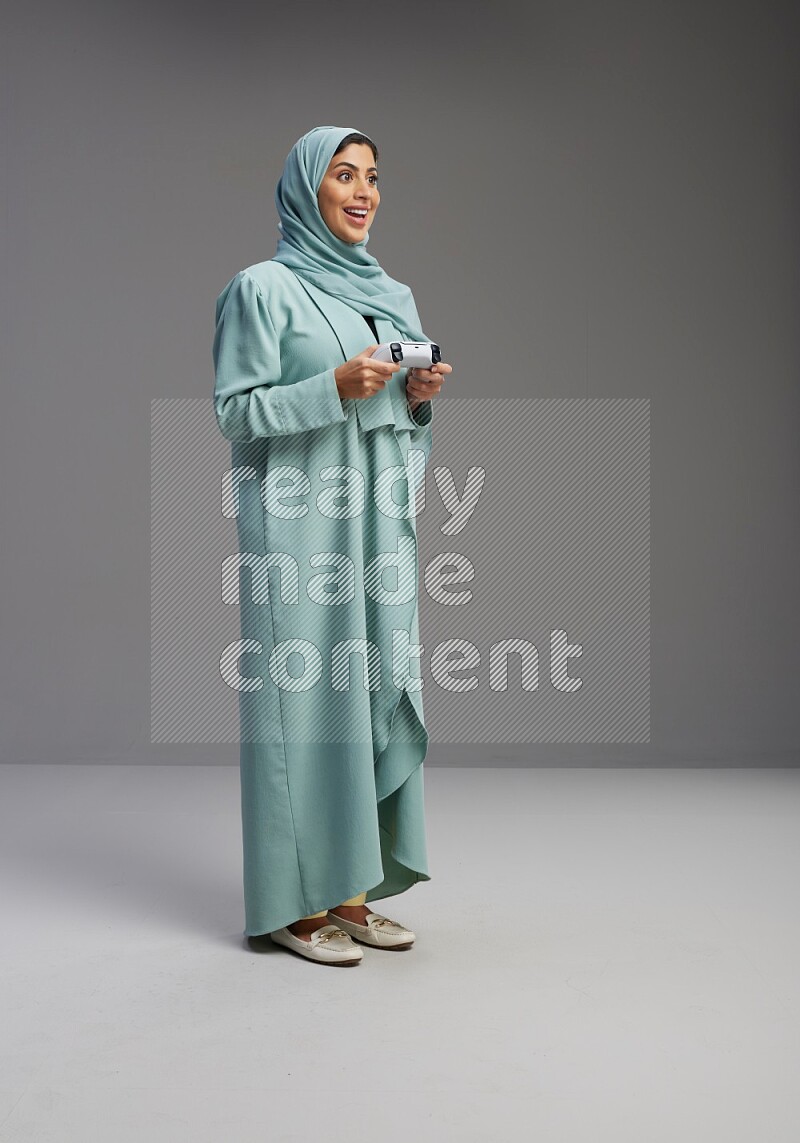 Saudi Woman wearing Abaya standing Playing Games on Gray background