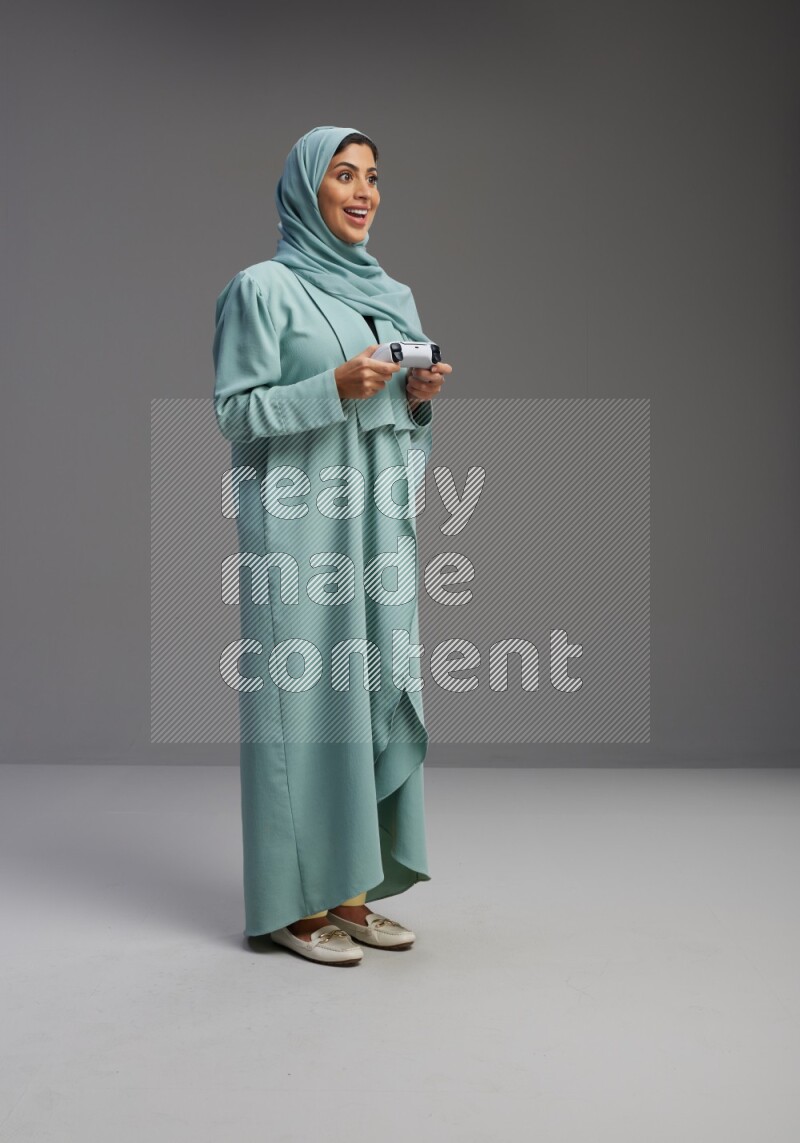 Saudi Woman wearing Abaya standing Playing Games on Gray background