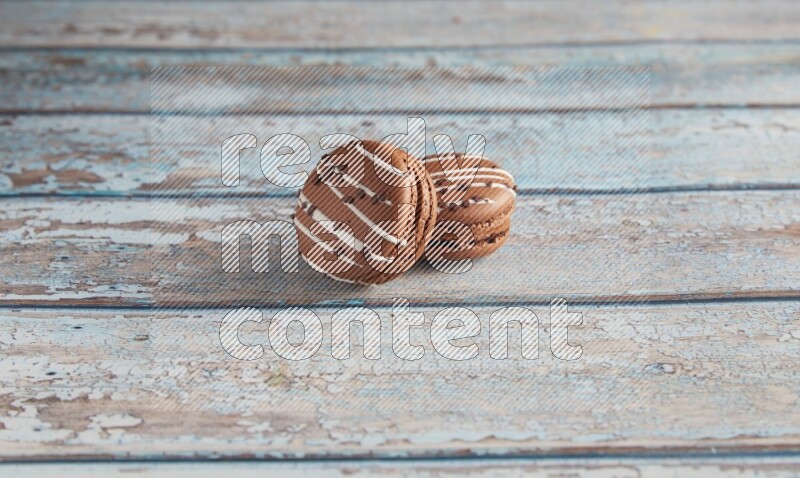 45º Shot of two Brown white  Chocolate Caramel macarons on light blue wooden background