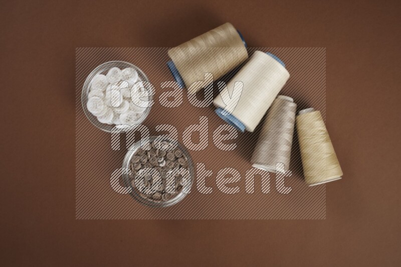 A white and brown collection of sewing and tailoring tools arranged on a brown background