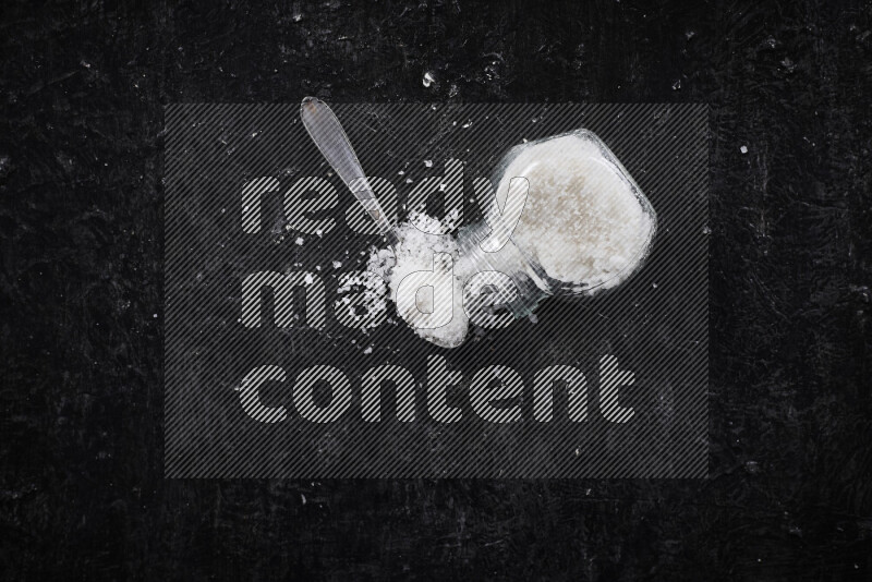 وعاء زجاجي ممتلئ بملح البحر الخشن على خلفية سوداء