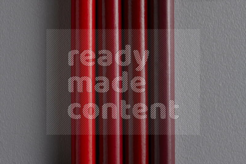 A collection of sharpened colored pencils arranged showcasing a gradient of red hues on grey background