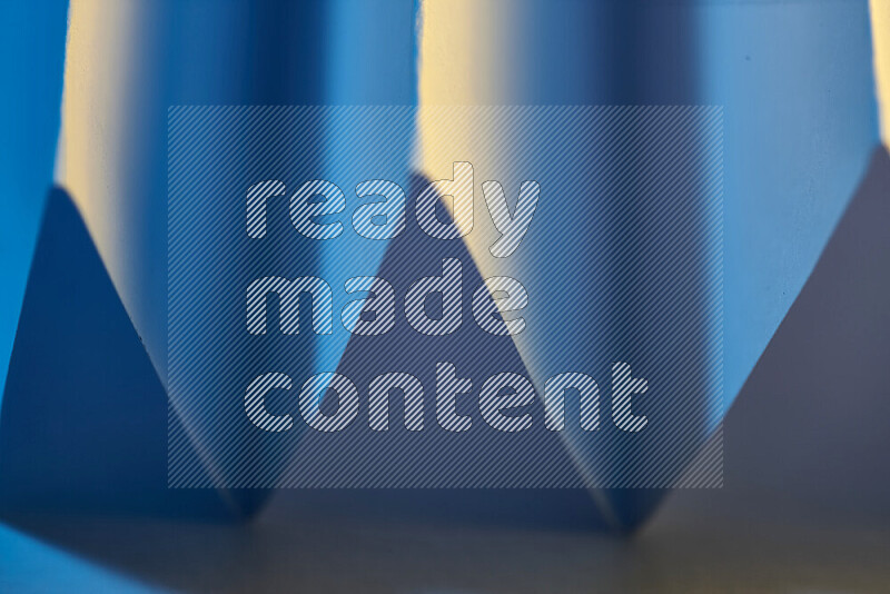 صورة مجردة مقربة تظهر طيات ورقية هندسية حادة بتدرجات اللون الأزرق مع درجات لونية دافئة