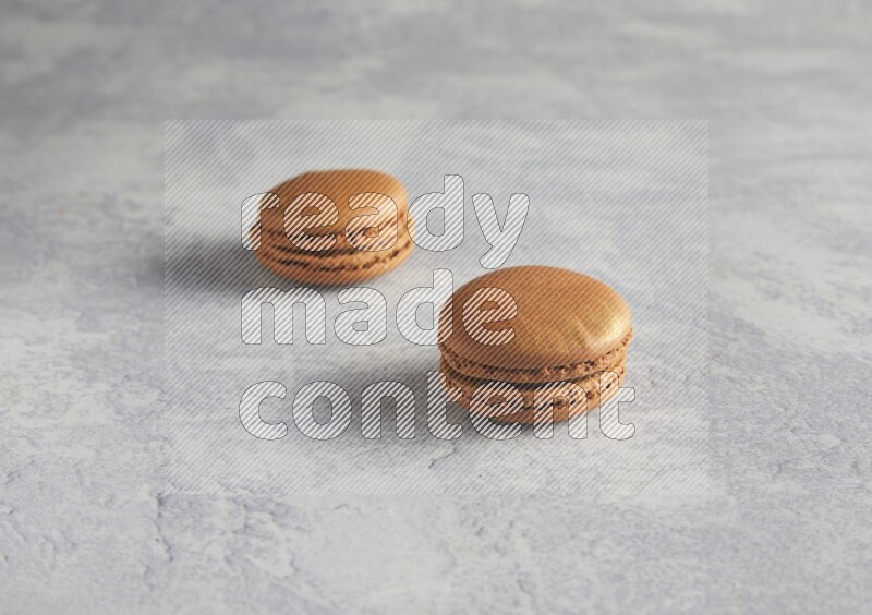 45º Shot of two Brown Coffee macarons  on white  marble background